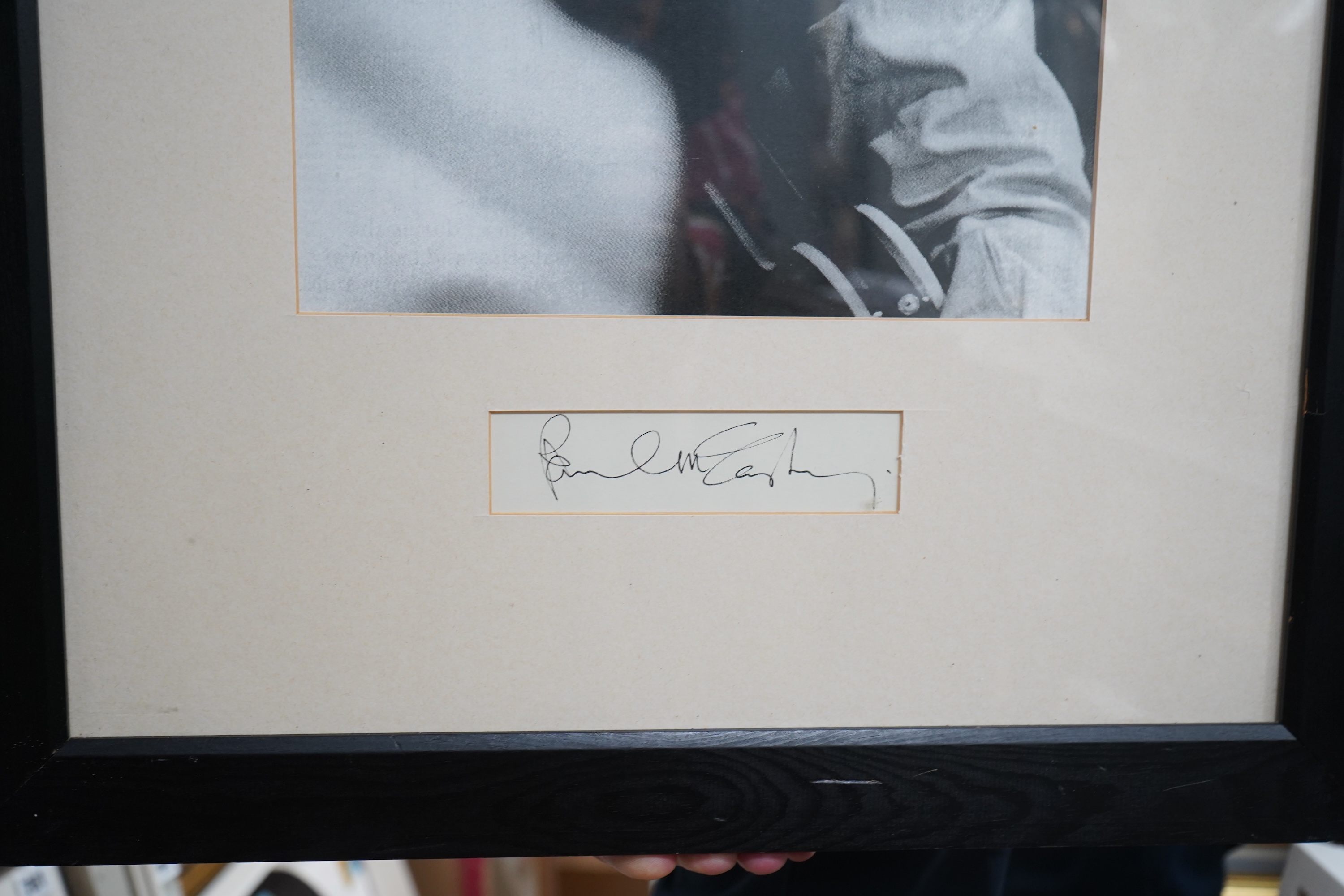 A framed autograph of Paul McCartney, signed in black ink, mounted below a black-and-white photograph of McCartney taken from a 1960s image, dimensions of frame; 66 x 48cm